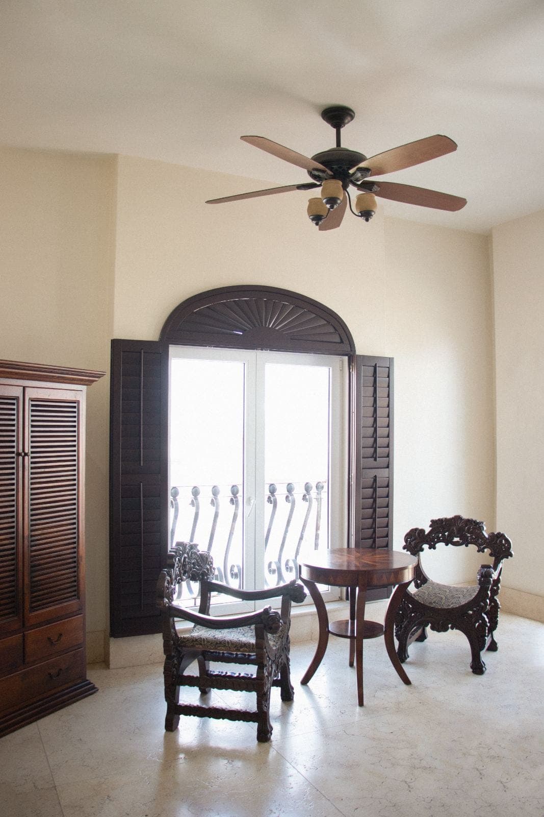 Sitting area with carved chairs, wooden armoire and balcony