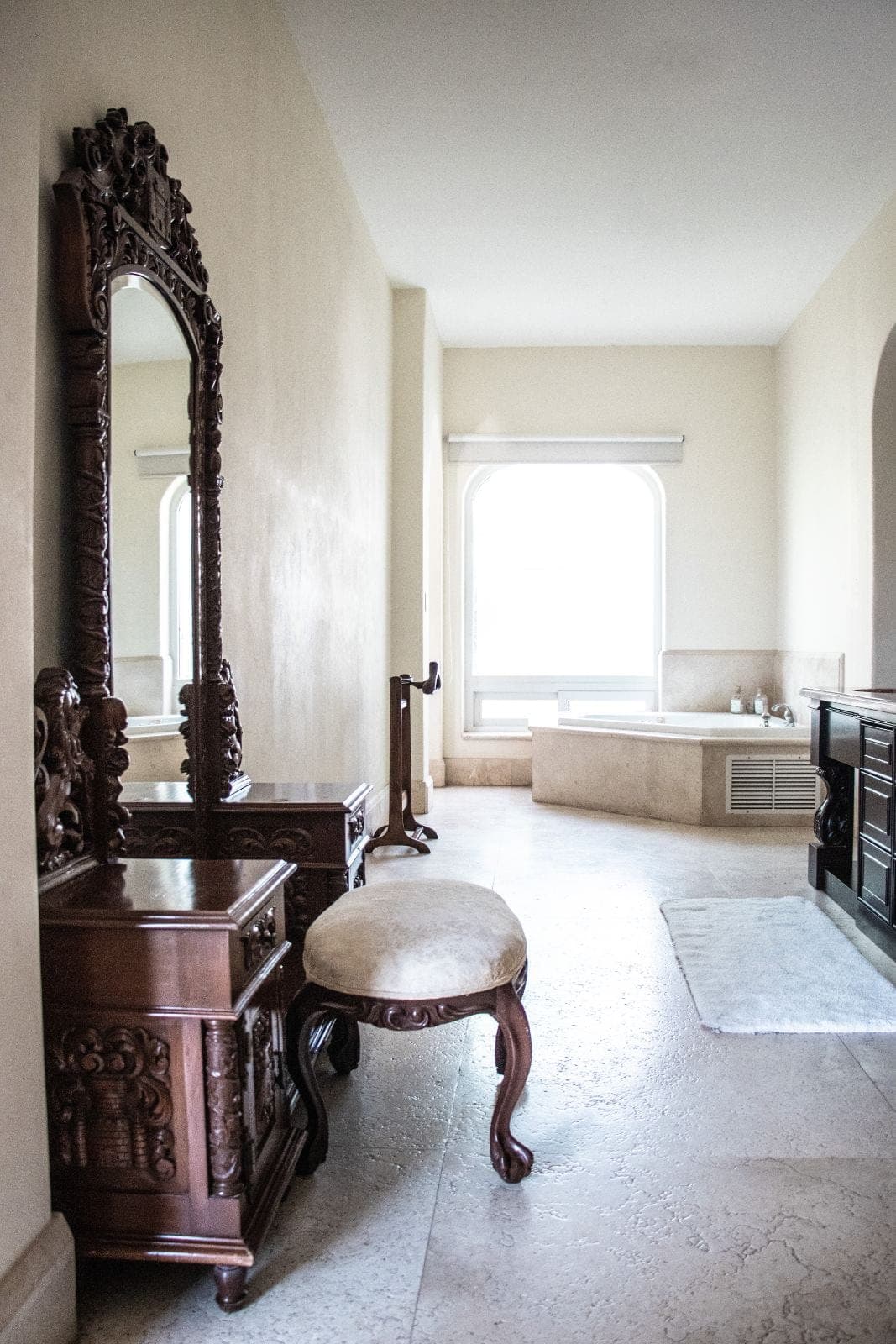 Baño de mármol con jacuzzi y tocador antiguo tallado