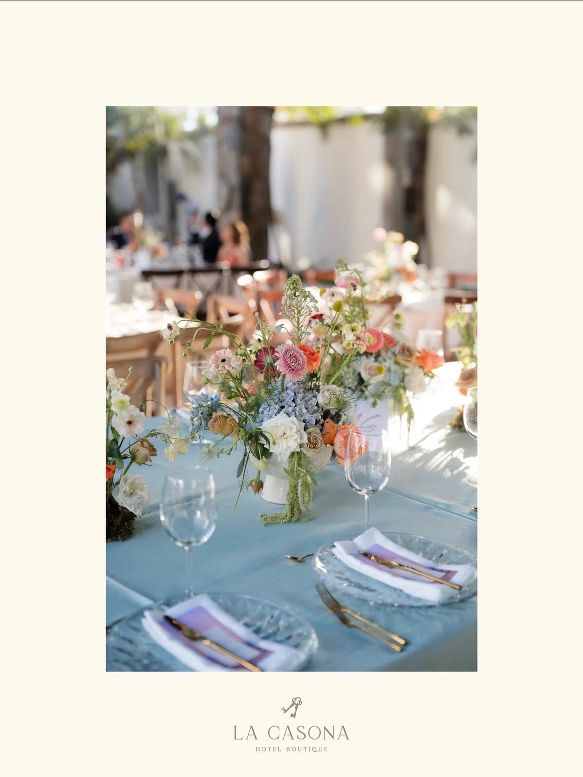 Centro de mesa en tonos pastel sobre mantel azul en una boda en el jardín
